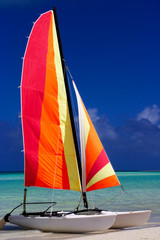 Colorful catamaran on the beach in the Caribbean with a blue sky.