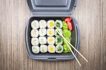 Sushi rolls in a container on a wooden table. top view,