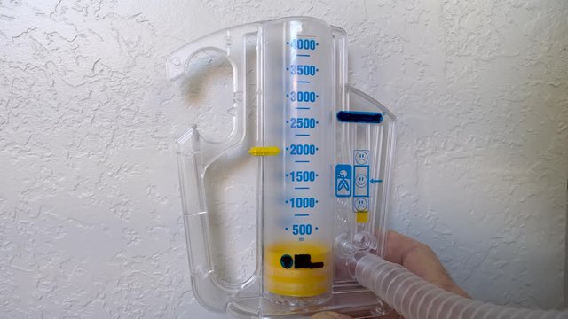 Hand holding incentive spirometer while exercising breathing and testing lung capacity.