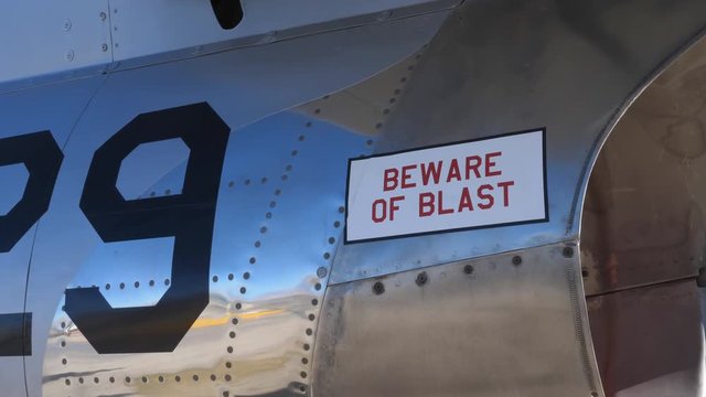 Pan right to BEWARE of BLAST near engine of 1950s fighter jet. F-86 Sabre. Handheld shot with stabilized camera.
