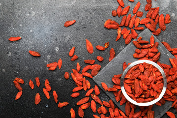 Dried red goji berries on gray background - useful and healthy food concept, flat layout with the place for text, top view