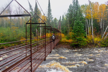 Woman hiking across suspension bridge over river