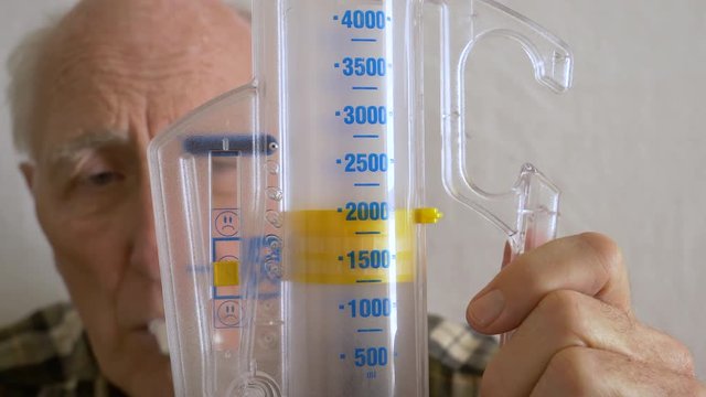 Aging senior practices breathing with incentive spirometer device-Closeup
