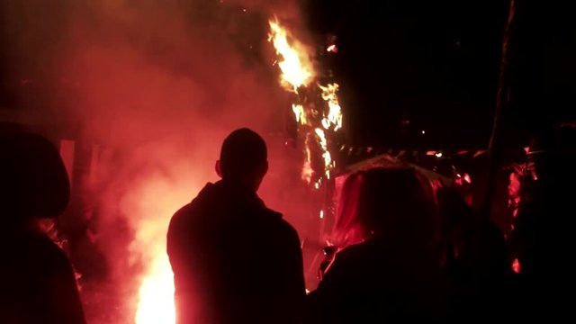 People around a bonfire, while a fake dummy is burning for a traditional carnival in Greece