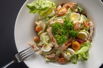 Caesar salad on a white plate on a dark background.