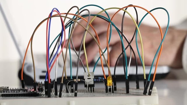 Maker, student or electronics engineer programming microchip prototype electronics circuit developed on breadboard