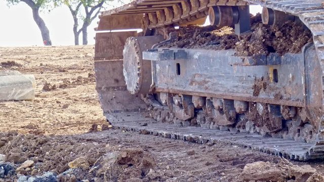 Close up of a excavators tracks as it moves across a construction site