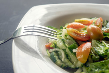 salad of cherry tomatoes and cucumbers on a white plate on a dark background