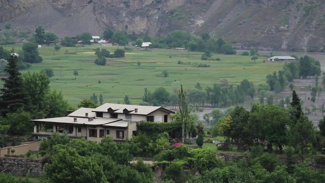 Wind blows across a village's valley below the mountains in Northern Pakistan