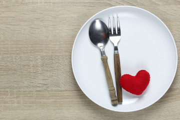 Wooden spoon and dish and red heart on wooden floor with copy space.