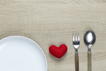 Wooden spoon and dish and red heart on wooden floor with copy space.