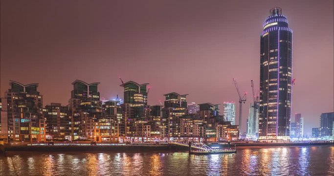 River view of high futuristic buildings in London, St George Wharf with neon effects lights and reflections on the river, nighttime, 4k