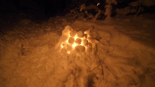 Snow lantern fire in winter forest. handmade Firecamp bonfire outdoors in the frozen icy ice snow.