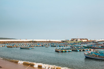 Vizhinjam fishing habour with colorful fishing boats in the foreground. Vizhinjam International Seaport is a proposed port by the Arabian Sea at Thiruvananthapuram in India. 