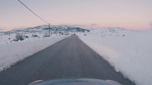 Driving on a snowy mountain road. Returning from Ziria ski center. Sunset colors in the horizon.