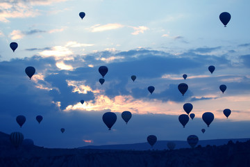 Many passenger balloons fly against the background of dawn in the clouds