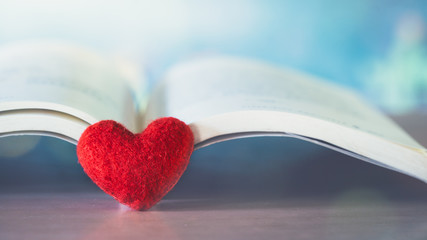 close up a red heart with book or bible on wooden table, love concept.