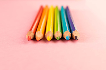 Colored pencils isolated on pink background. LGBT people of color.
