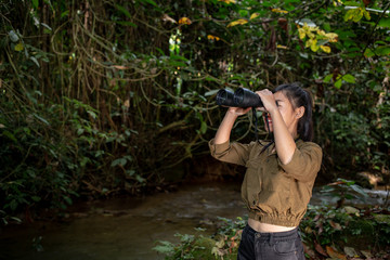 The woman climbs a binoculars to travel and has a happy smile.