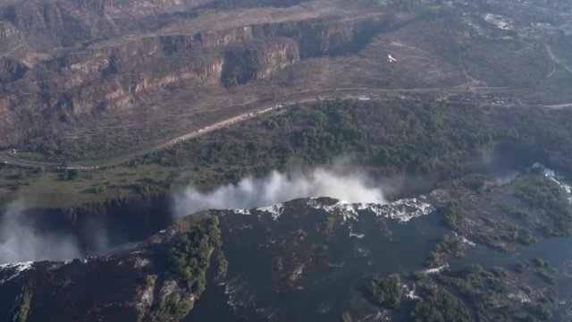 Aerial shot sees a microlight aircraft fly over the Victoria Falls in Zimbabwe, Africa.