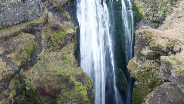 Aerial view of the scenic waterfall Gljufrabui in Iceland. Copter move away from the turbulent flow of water. 4k