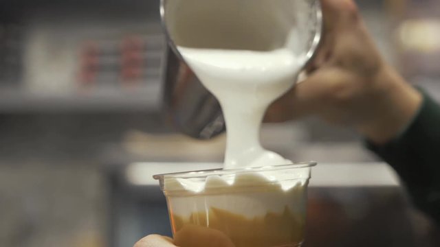 Pouring frothy milk over freddo cappuccino in slow motion