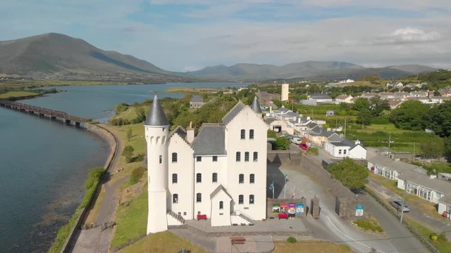 Fantasy castle in foreground set beside river and mountain range in background