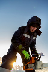 Portrait of a fitter in an orange vest with a chainsaw in his hands