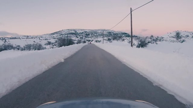 Driving on a snowy mountain road. Returning from Ziria ski center. Sunset colors in the horizon.