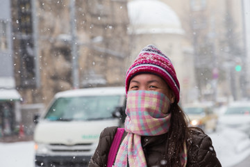 Beautiful and happy girl with scarf cover mouth in winter snowy day outdoors