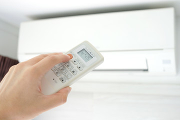 Man's hand using remote control open The air conditioner is cooled to 25 degrees Celsius in his bedroom. Health concepts and energy savings