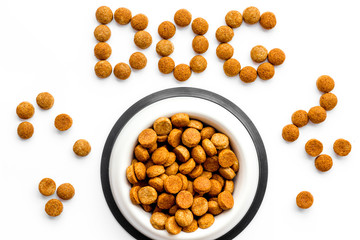 Dog food. Dry food in bowl, word dog lined with food on white backgorund top view