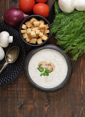 Champignon mushroom cream soup in bowl on wooden background. Rustic style. Top view.
