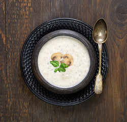 Champignon mushroom cream soup in bowl on wooden background. Rustic style. Top view.