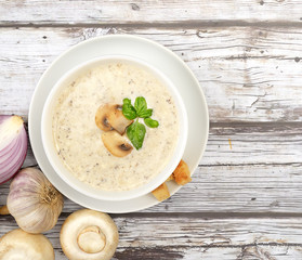 Champignon mushroom cream soup in bowl on wooden background. Rustic style. Top view.