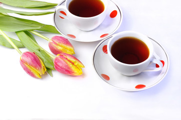 Tea for Two. Two cups of tea and a bouquet of red tulips