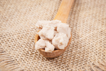 Fresh crumbled yeast on spoon for baking different dough or bread