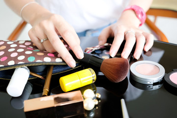 hands of a beautiful slender woman, she is looking for her cosmetics in the pocket colorful fashion and she was holding a makeup brush.