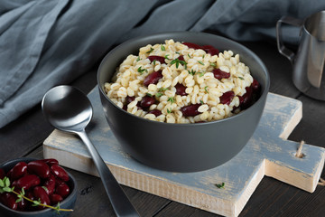 Pearl barley porridge in a plate on a black wooden background