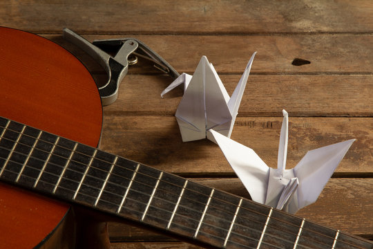 Paper bird with guitar and musical instrument on wooden table