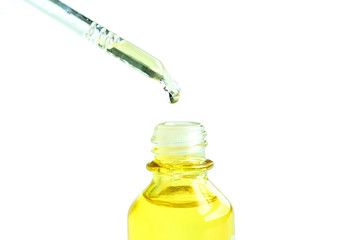 Dropping serum collagen moisturizer of face into clear yellow bottle soft light background. Protector skin Treatment facial essence oil, Vitamin C. Beauty and spa Concept.