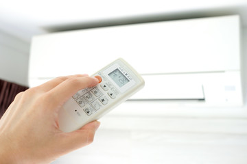 Man's hand using remote control open The air conditioner is cooled to 25 degrees Celsius in his bedroom. Health concepts and energy savings