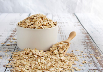 Dried oats or oatmeal in a bowl on the wood table. Its are a nutrient-rich food associated with...