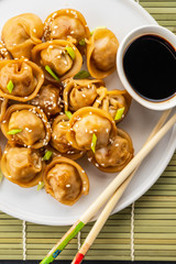 Stone slate tray with various types of korean dumplings, on the mat, dark brown stone background. Top view.