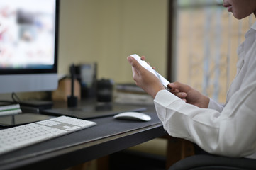 Cropped shot woman using mobile phone on office desk.