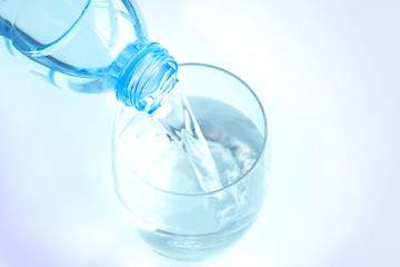 Pour pure water from a bottle of mineral water into a glass.