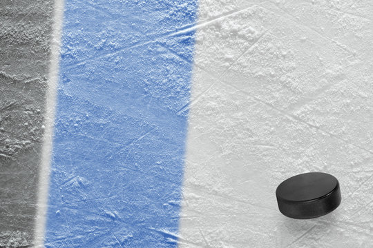 Hockey puck and fragment of the ice arena with black and blue lines