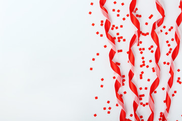 Red satin ribbons and confetti background with copy space