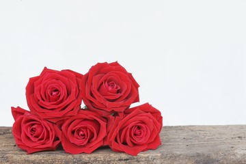 Group of lovely blooming red color rose flower decorated with petals on wood table background, sweet valentine present concept
