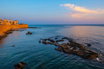 Alghero, Sardinia, Italy - Summer sunset view of the Alghero old town quarter with historic defense...